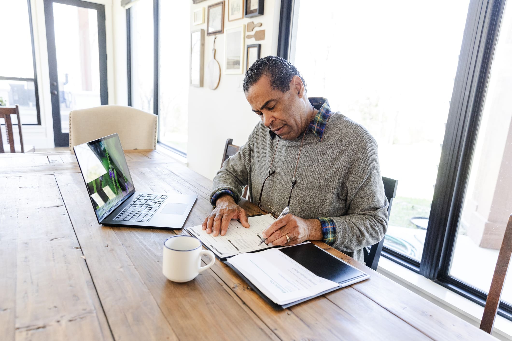 Individual writing notes next to laptop