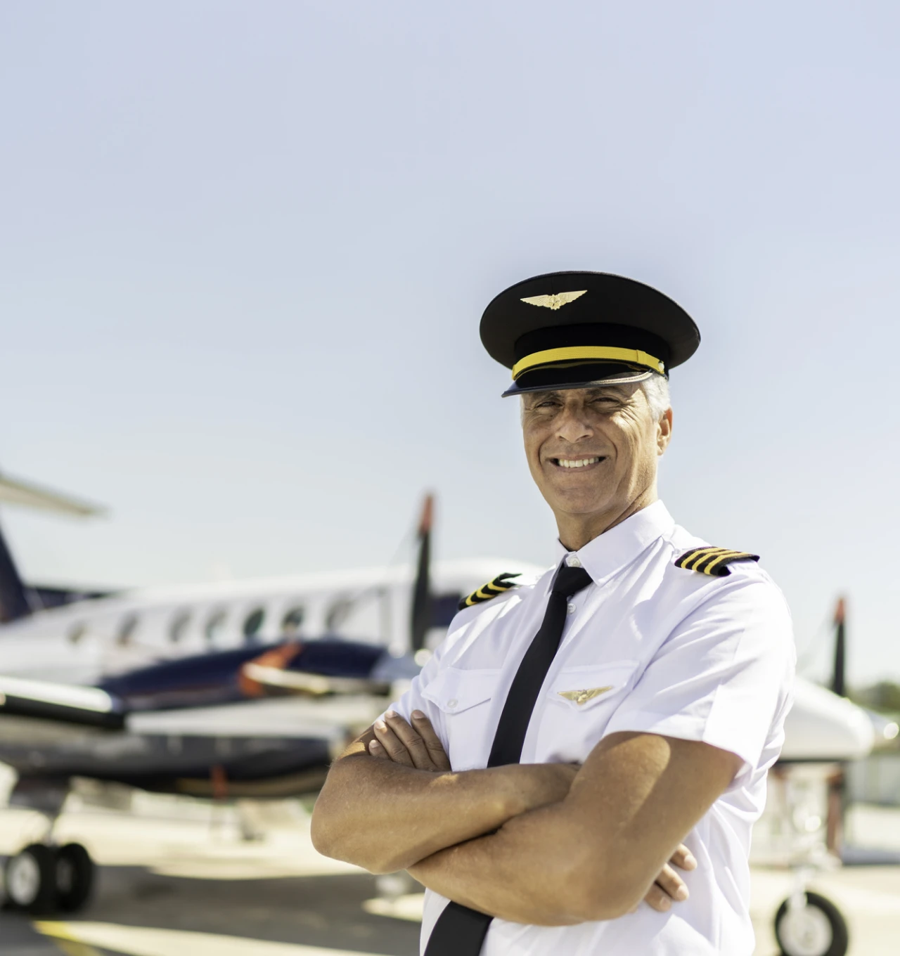 Smiling pilot with folded arms outdoors